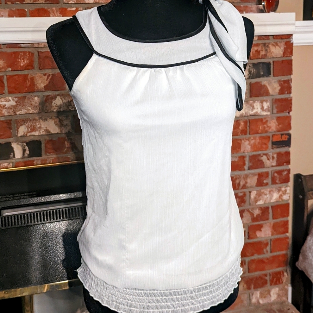 White sleeveless top with black neck trim